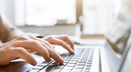 Hände tippen auf einer Laptop-Tastatur Hände tippen auf einer Laptop-Tastatur
