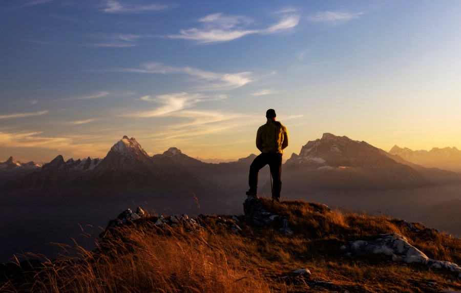 Bergsteiger steht auf Berg und schaut in den Fernblick