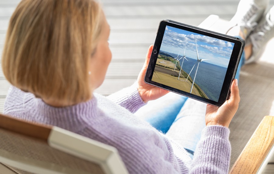Magdalena Neuner sits in an armchair and watches the Pangaea Life investment trip on a tablet